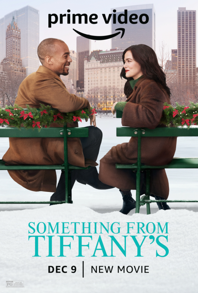 Ethan and Rachel sitting on green benches bedecked with greenery and red bows. They are turned to look at each other, both in brown coats. The city is in front of them. Above says Prime Video and below the title and release date.