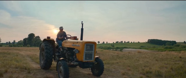 Halina in her farm clothes on her yellow tractor as the sun is setting. 