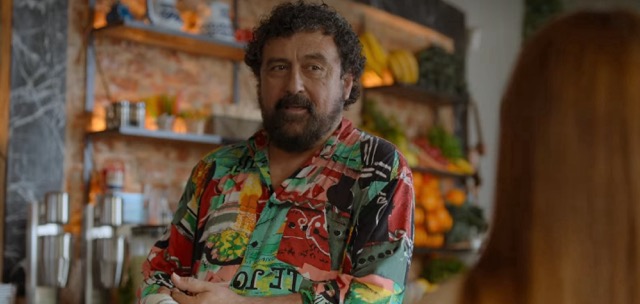 Sebas, a white man with a beard, standing in behind the bar in his café.