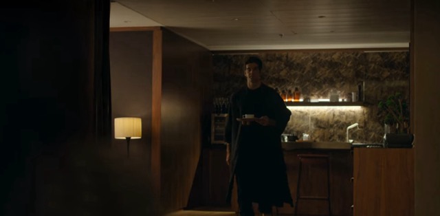 Óscar in his black robe walking toward Valentina while holding a cup of tea.