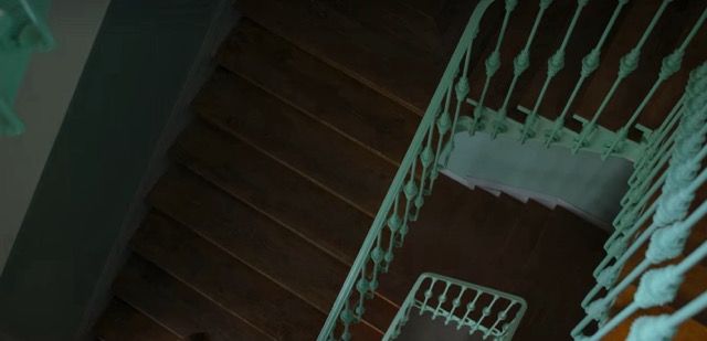 Several flights of stairs from above that have an aqua colored metal railing.